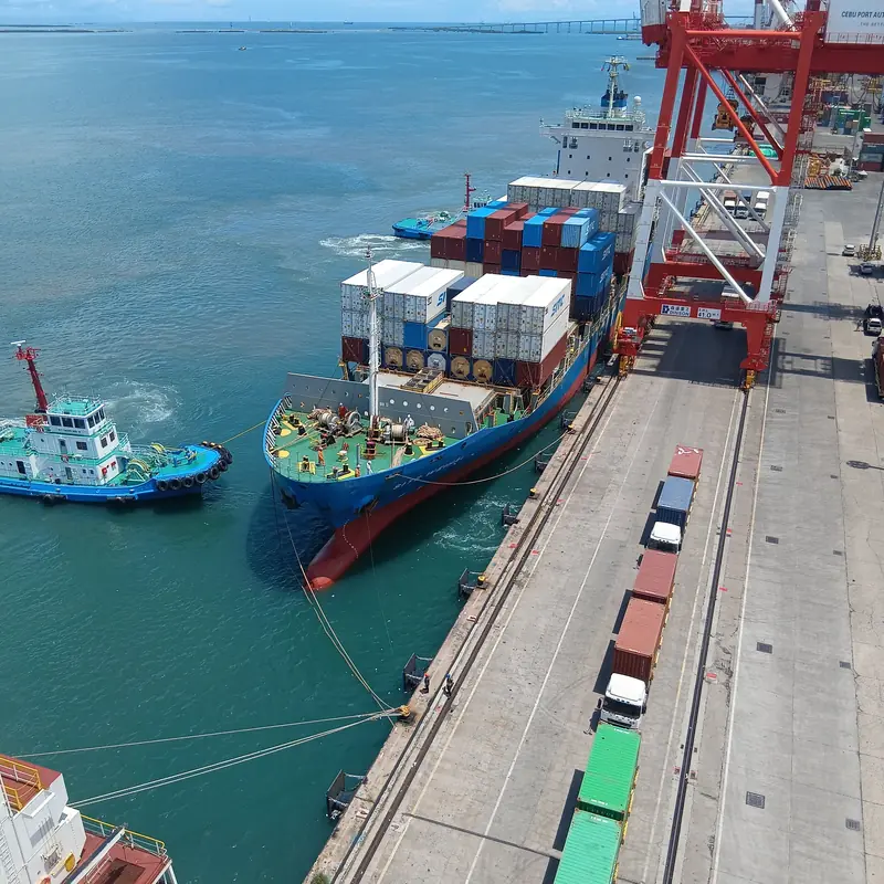 Porte-conteneurs et remorqueurs le long d'un quai de terminal, vue aérienne