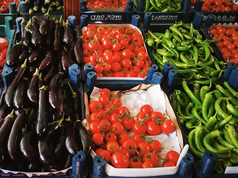 Étal de tomates, aubergines et piments frais en cagettes